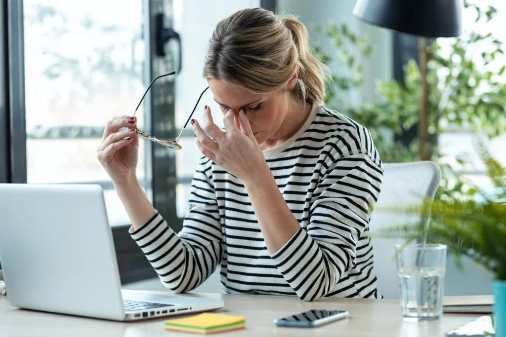 stressed mature business woman looking worried, tired and overwhelmed while working with laptop