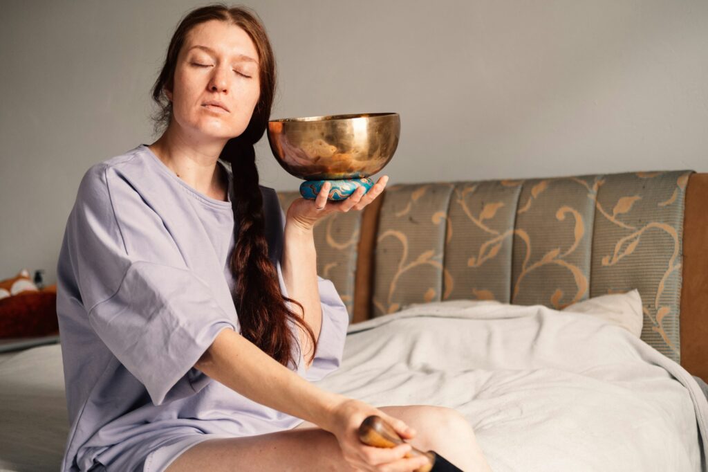 woman in deep meditation with a Tibetan singing bowl, engaging in a peaceful sound healing practice